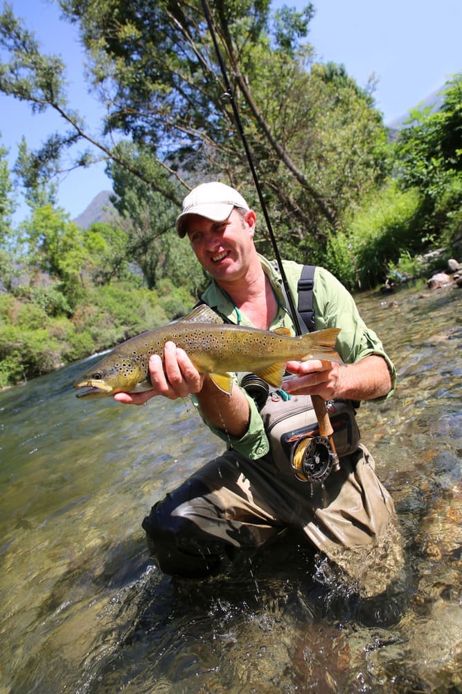 Things to Do in Salida Colorado - fisherman holding up fish to the camera fishing in Arkansas River near Salida Colorado Things to Do in Salida Colorado - fisherman holding up fish to the camera fishing in Arkansas River near Salida Colorado